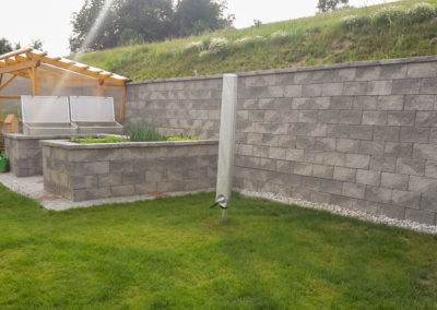 Stützmauer ca. 2 m hoch und integr. Hochbeete aus Beton-Mauersteinen in Felsen-Grau meliert mit Abdeckplatte und trocken verlegt